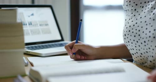 Young Adult Studying with Textbook and Laptop