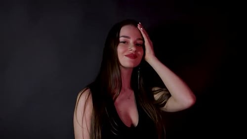 Sexy fashion model posing alone dressed in black dark studio red light