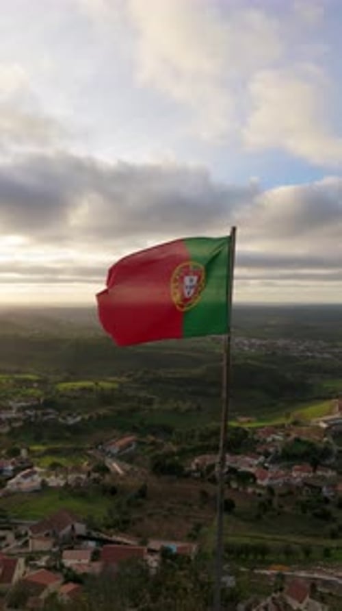 Portuguese Flag Waving over Small Village at Sunrise
