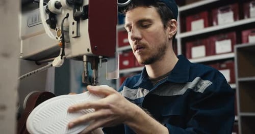 A Redhaired Man in a Blue Uniform Sews the Sole of a Shoe on a Special Machine at a Shoe Factory