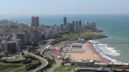Panning aerial movement above the Mar del Plata city tall buildings and sandy beaches, Argentina.