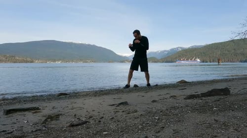 Adult Man Practicing Martial Arts and Shadow Boxing on the Beach