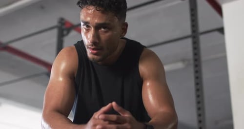Sweating and resting, man in gym taking break from workout