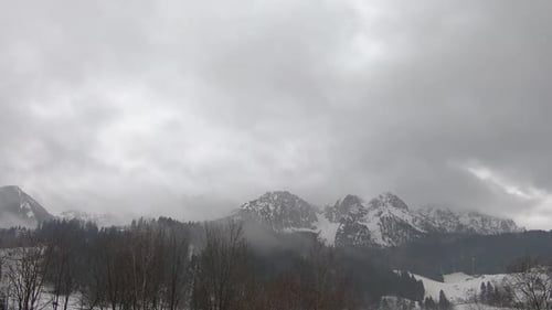 The movement of rain clouds over the mountain range. Camera movement from left to right. Time Lapse.