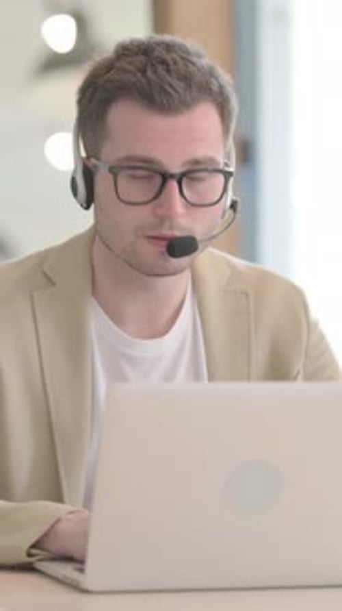 Young Businessman with Headset Looking toward Camera in Call Center, Vertical Video