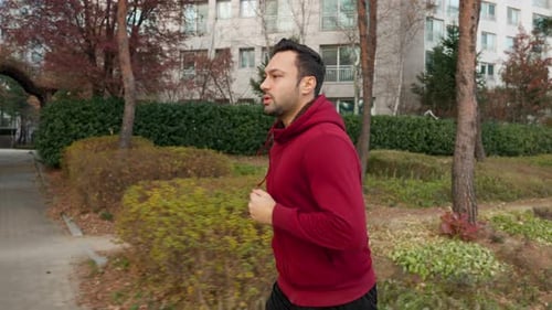 Young European man running exercising outdoors in city park