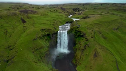 Majestic Waterfall Flowing Through Lush Green Landscape