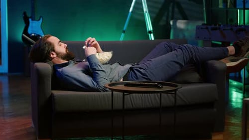 Man Relaxing on Couch and Eating Popcorn