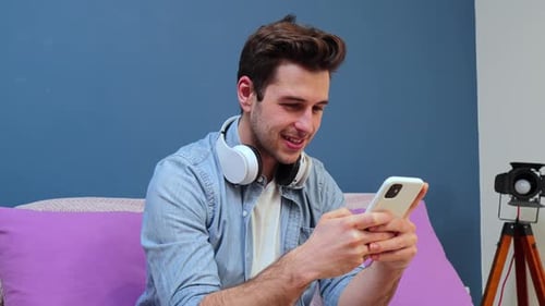 Young adult on couch smiling at his phone