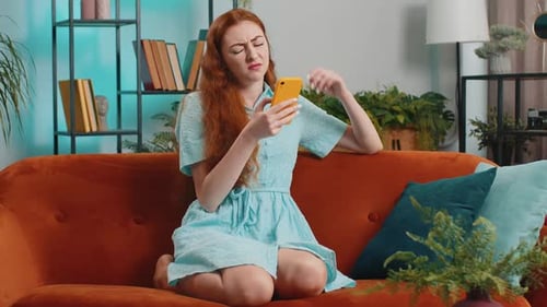 Woman with Phone Looking Confused on Couch