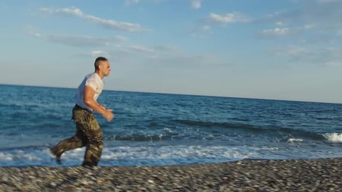 Man Running and Exercising on Beach Near Ocean