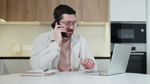 Freelancer Doing Work Remotely and Speaking with Customer Through Phone Indoors