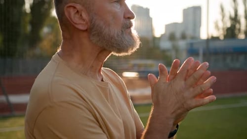 Mature Man Rubs Hands Outside in Sunlight