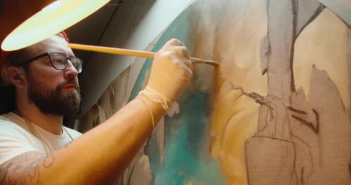Male Artist Paints a Canvas in His Art Studio