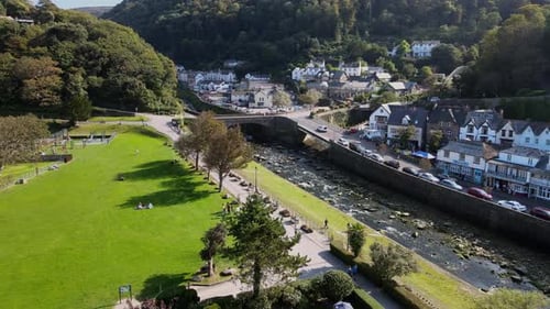 Vidéo aérienne de la rivière East Lyn et du parc de Lymouth, dans le Devon, des voitures britanniques traversant un pont routier, des personnes assises