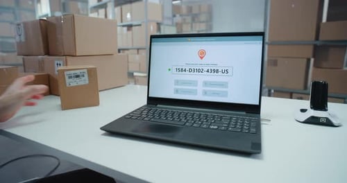 Logistics Specialist Scans Code to Check Parcel Routing on Laptop in Delivery Tracking Software