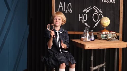 Cute Girl with Magnifying Glass in Classroom