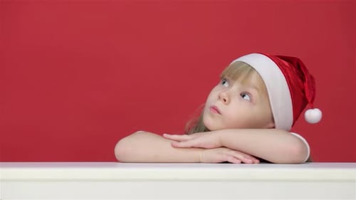 Child Wearing Santa Hat Smiling Against Red Backdrop