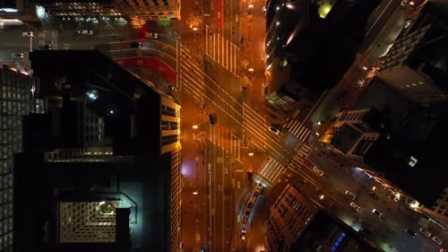 Top Down Footage of Cars Passing Through Road Intersection in Urban District Illuminated Streets in