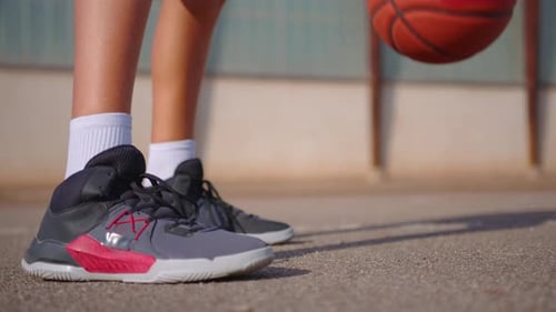 Closeup of Sportswoman Bouncing Basketball Ball Training on Ground Floor of the Court