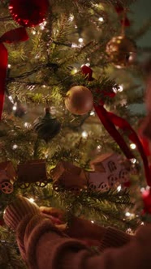 Woman Decorating Christmas Tree at Home at Night
