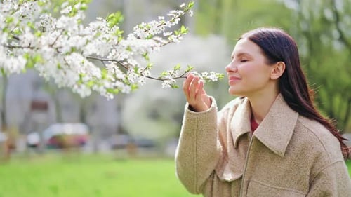 Happy Woman Smelling Blossoms in Spring Park
