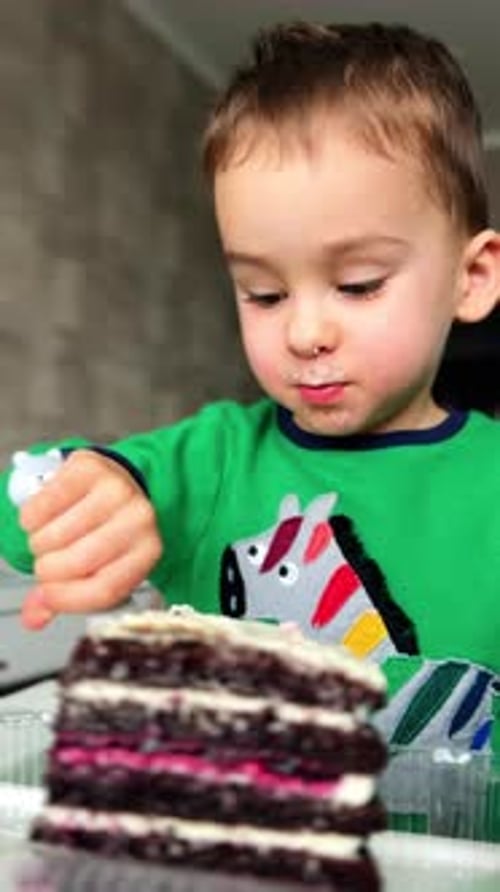 Pretty small boy eating cake. Baby boy eating sweets portrait. Vertical video.