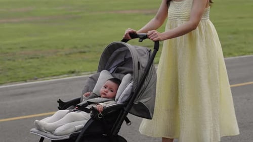 infant baby in stroller with mother pushing while walking in the park