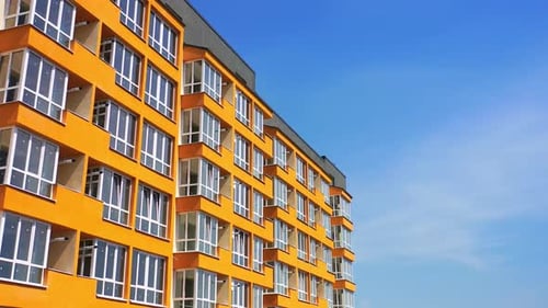 Block of flats with large balconies. Facade of a new high rise building on blue sky backdrop.