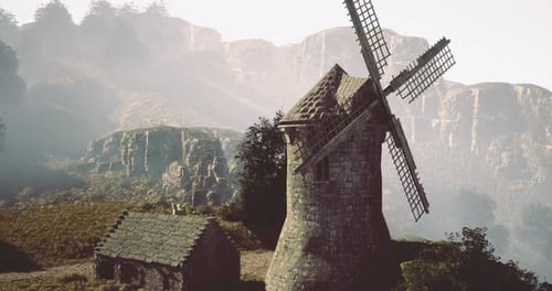 Moulin à vent rustique debout dans les montagnes brumeuses au crépuscule