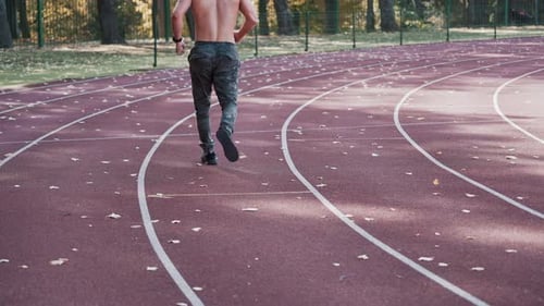 Back view of a man jogging on the stadium.