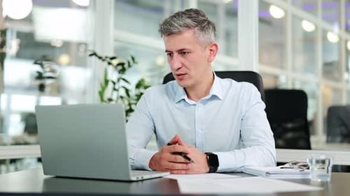 Focused Business Professional Engaged in an Online Video Call at a Modern Office Desk