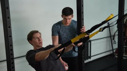 Beginner Sportsman Doing Fitness Trx Exercises in Gym with Personal Fitness Trainer Male Using