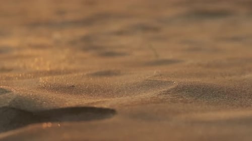 Kleine Sandpartikel wehen in Zeitlupe über Miniaturdünen