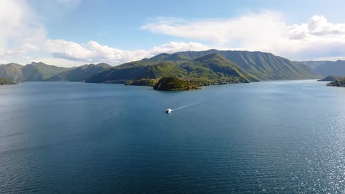 Aerial drone view of a boat on Lake Como, Italy surrounded by mountains