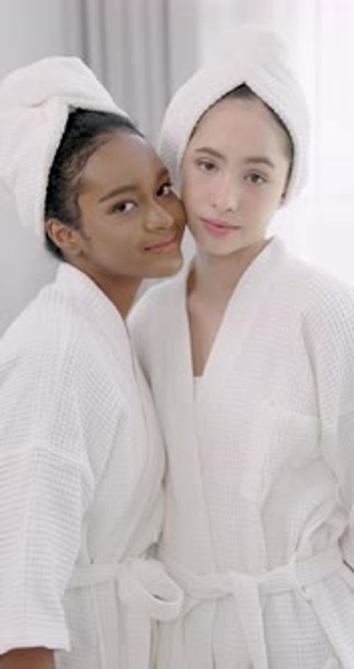 cadre au ralenti d'adolescentes africaines et asiatiques souriant vivement dans des peignoirs blancs pendant