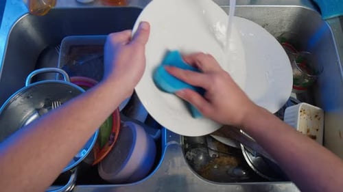 Top View of Male Hands Washing Dishes in the Kitchen