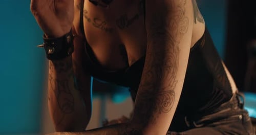 Tattooed Woman Posing in a Dimly Lit Room