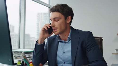 Man on Smartphone Looking at Financial Charts in Office