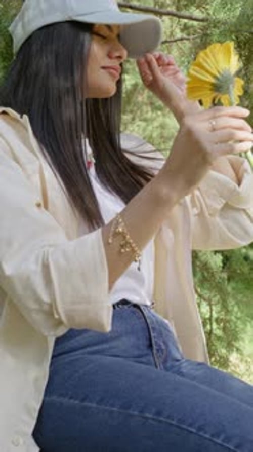 Close Up Woman Smelling Yellow Flower In Sunny Forest