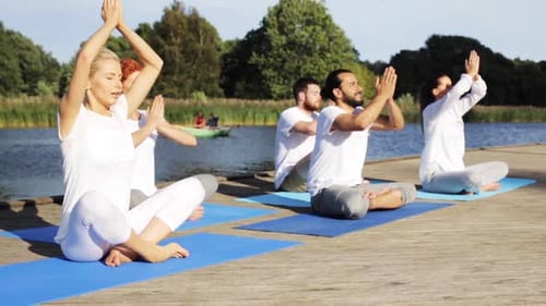 Group Practicing Yoga on Dock Near Lake on Sunny Day