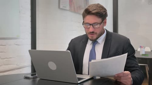 Man at Desk Reacts to Good News on Laptop