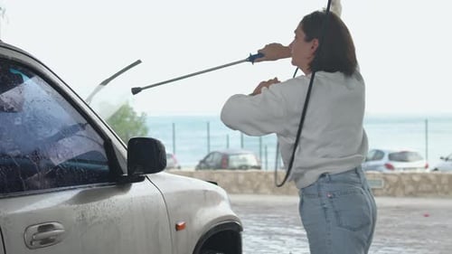 Woman Washing Car with Pressurized Water at Selfservice Wash Station