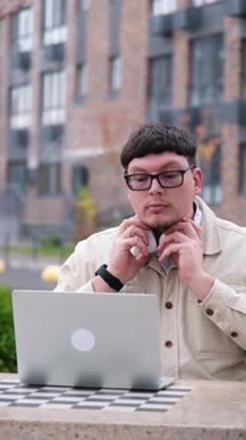 Serious middle aged man freelancer wearing casual clothe using laptop sitting on bench on the street