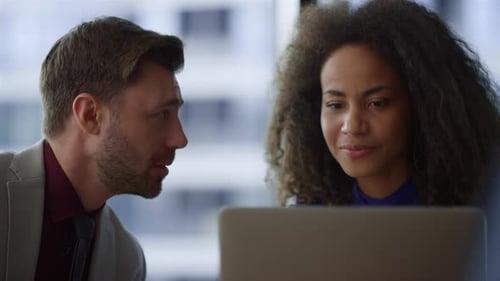 Multi Ethnic Business Couple Working on Computer Laptop Laughing in Corporate Building