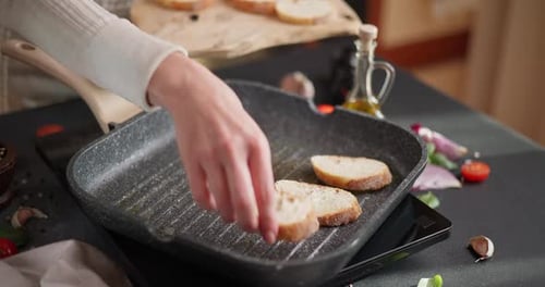 Woman Puts Sliced Baguette Pieces Onto Grill Frying Pan Making Grilled Bruschetta Bread
