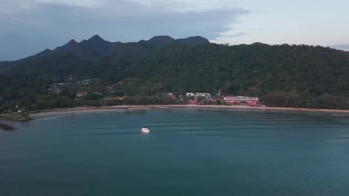 White Boat Sailing Near Tropical Island Coast at Dusk