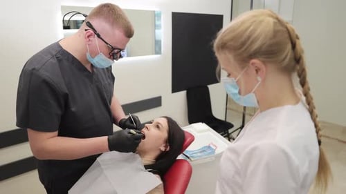 A Dentist Conducts an Oral Examination with Their Assistant in a Clinic for Patient Care