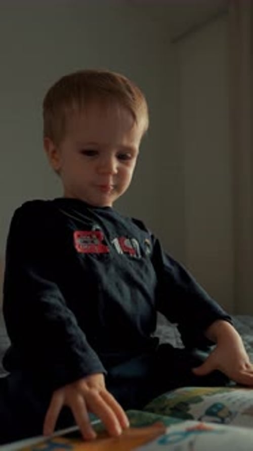 La verticale d'un enfant de sexe masculin focalisé examine un nouveau livre avec des images lumineuses