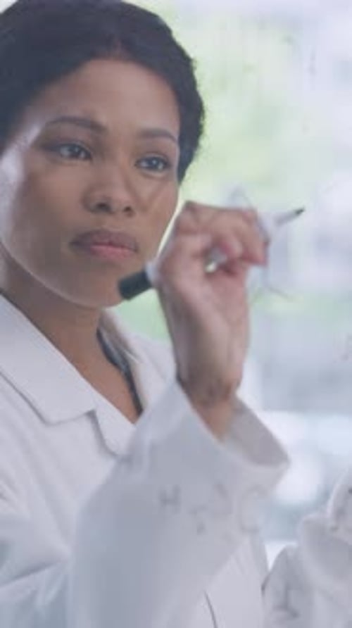 Scientifique, femme et écriture d'une formule sur une paroi de verre pour la structure d'une molécule, une piste médicamenteuse ou une innovation